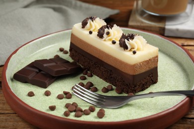 Tasty mousse cake, chocolate and fork on plate, closeup