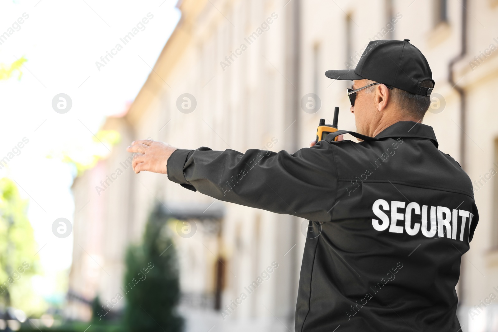 Photo of Male security guard using portable radio transmitter outdoors