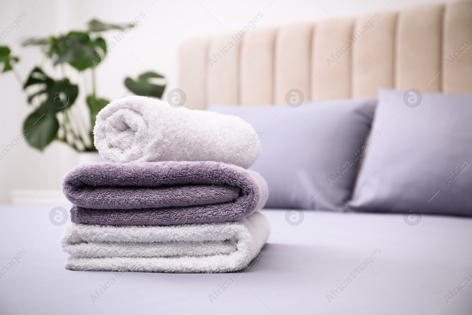 Photo of Soft clean towels on bed indoors. Space for text