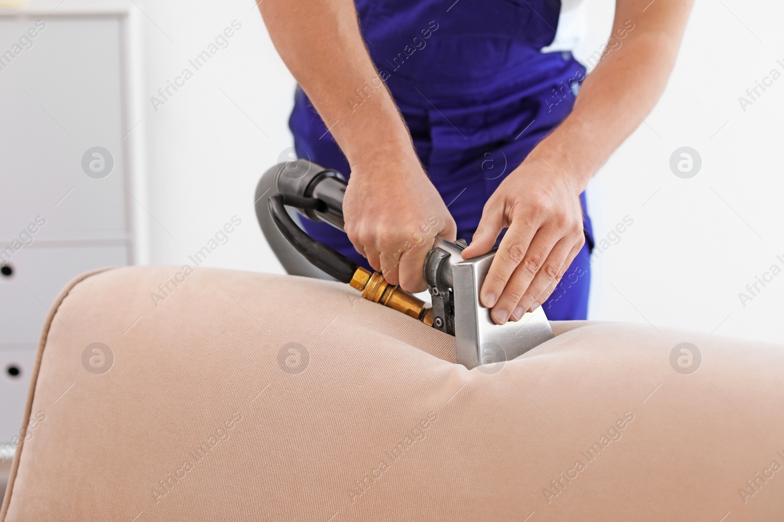 Photo of Dry cleaning worker removing dirt from sofa indoors