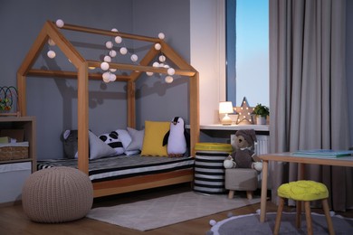 Stylish child room interior with comfortable house bed and toys