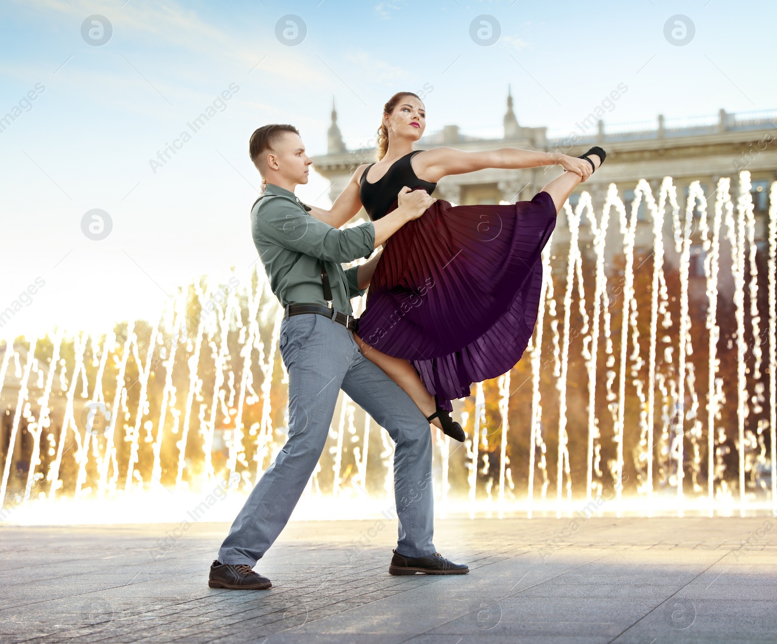 Photo of Beautiful young couple practicing dance moves near fountain outdoors