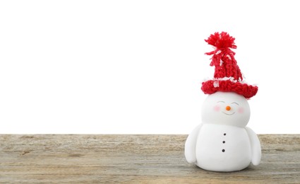 Photo of Cute decorative snowman in red hat on wooden table against white background, space for text