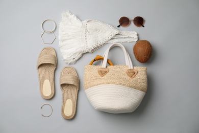 Stylish straw bag and summer accessories on grey background, flat lay