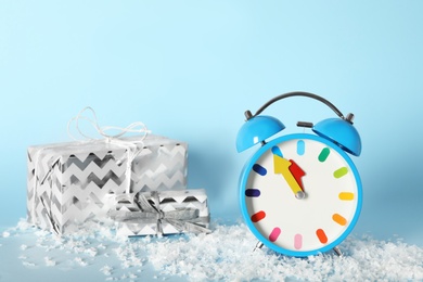 Alarm clock with Christmas decor on light blue background. New Year countdown