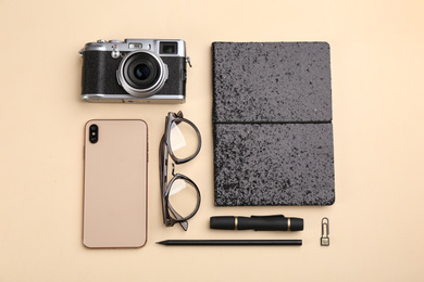 Photo of Flat lay composition with camera for professional photographer, smartphone and accessories on beige background