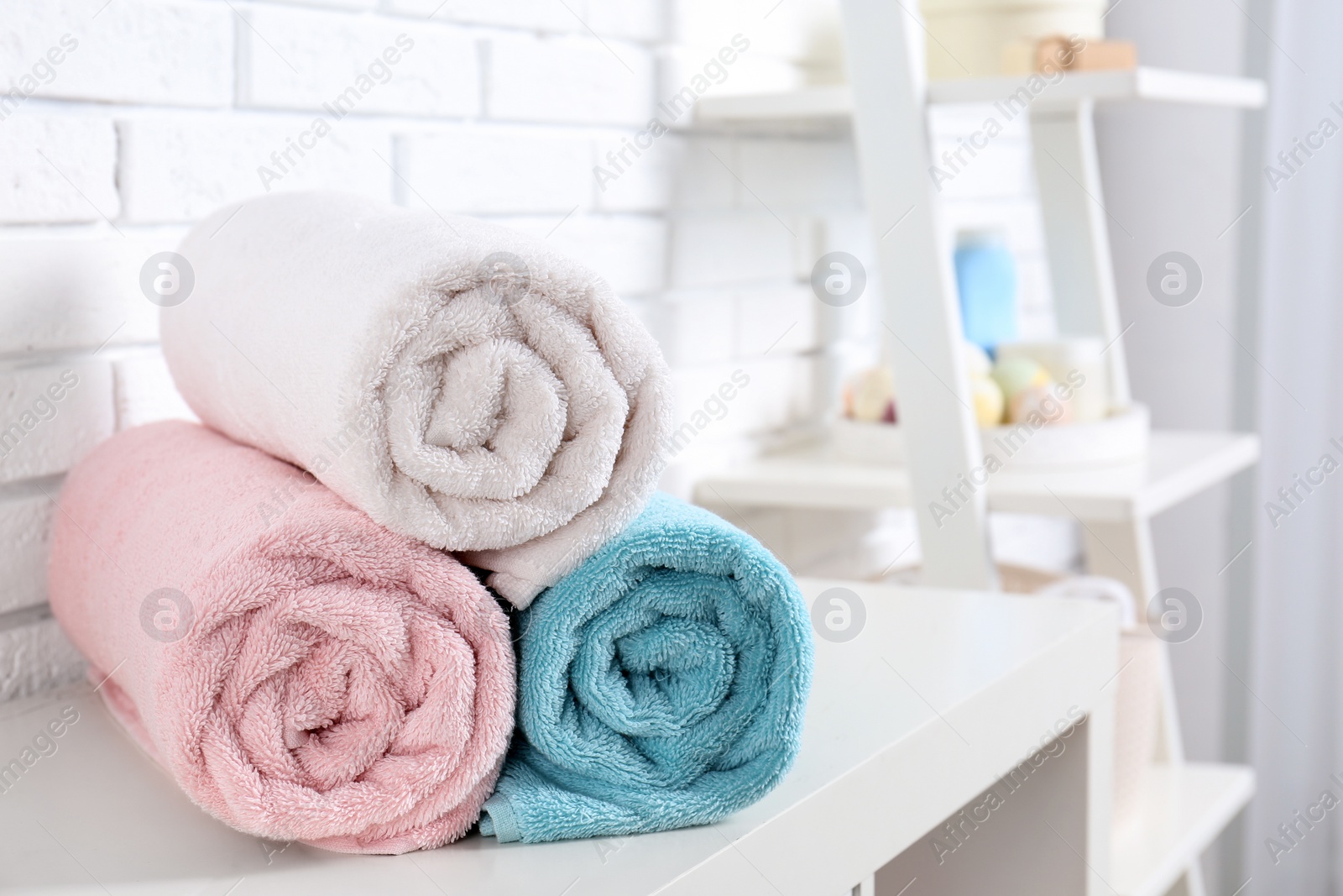 Photo of Rolled fresh towels on table in bathroom. Space for text