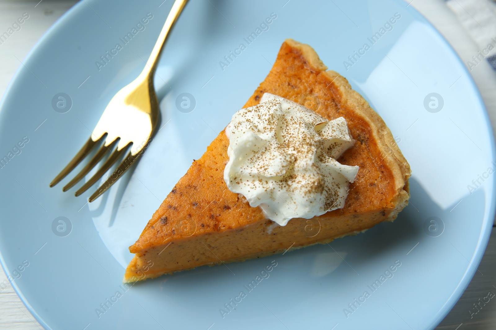 Photo of Piece of delicious pumpkin pie with whipped cream and fork on table, above view