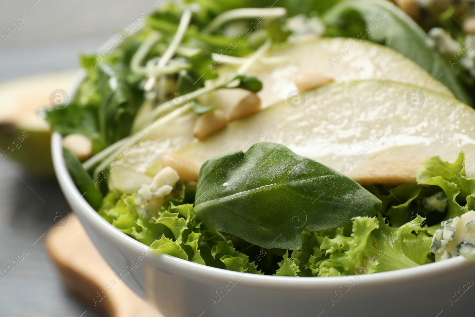 Photo of Fresh salad with pear in bowl on table, closeup