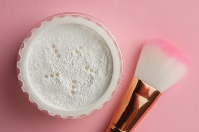 Photo of Rice loose face powder and makeup brush on pink background, flat lay