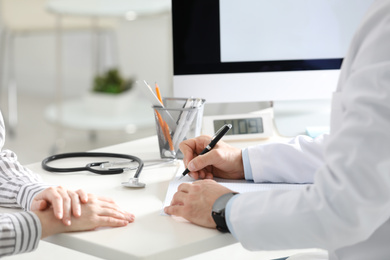 Photo of Doctor working with patient at desk in office, closeup