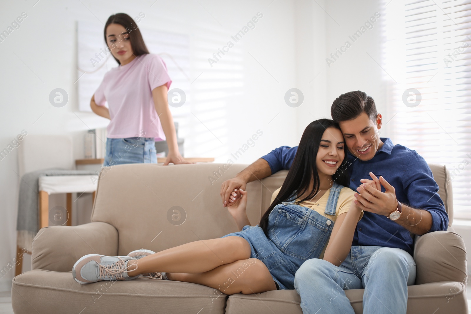 Photo of Unhappy woman feeling jealous while couple spending time together at home