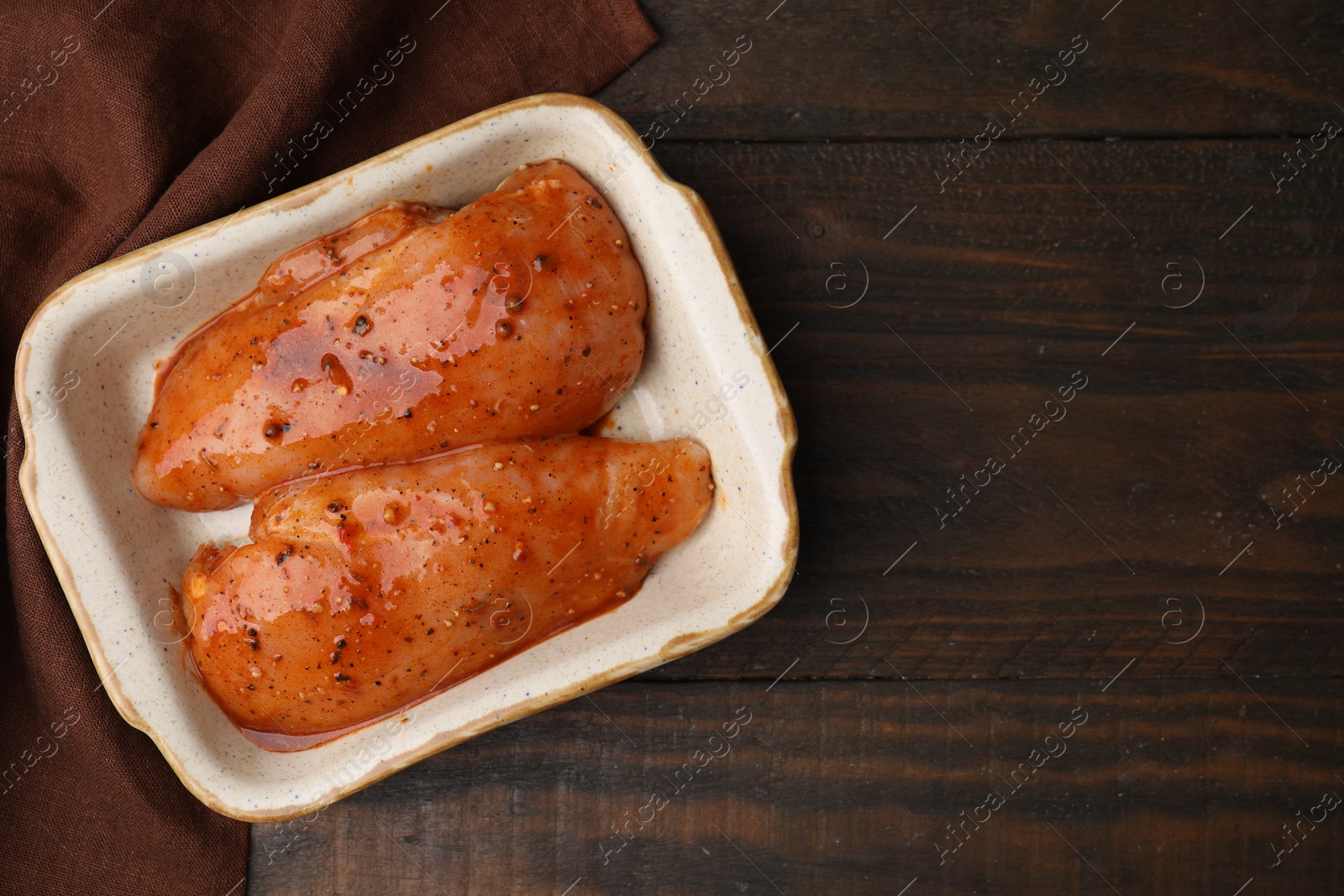 Photo of Raw marinated chicken fillets on wooden table, top view. Space for text