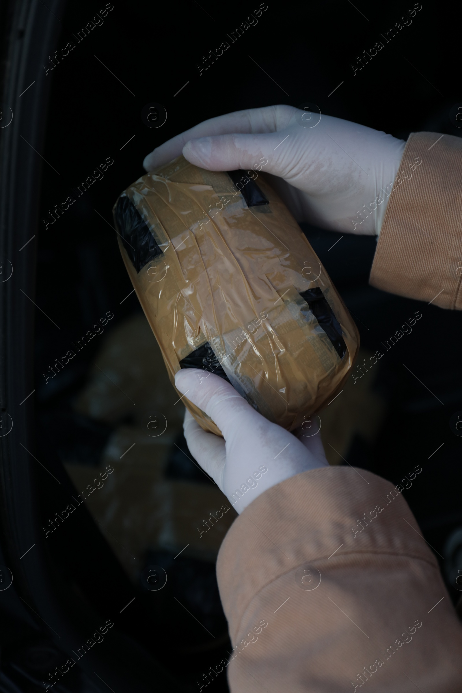 Photo of Man with package of narcotics on dark background, closeup