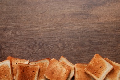 Photo of Slices of delicious toasted bread on wooden table, top view. Space for text