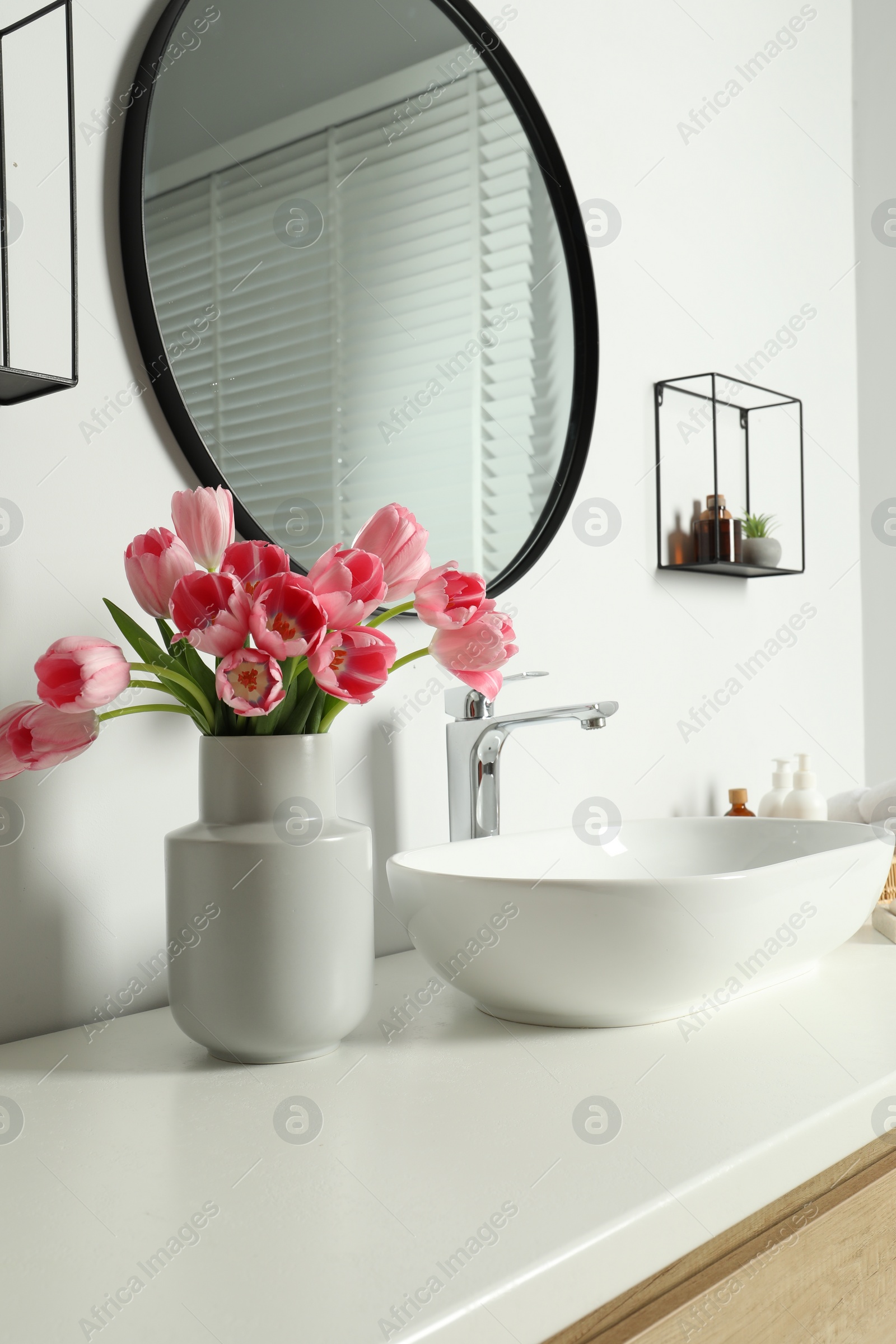 Photo of Vase with beautiful pink tulips near sink in bathroom