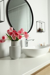 Vase with beautiful pink tulips near sink in bathroom