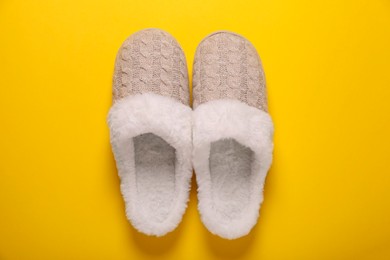 Photo of Pair of beautiful soft slippers on yellow background, top view