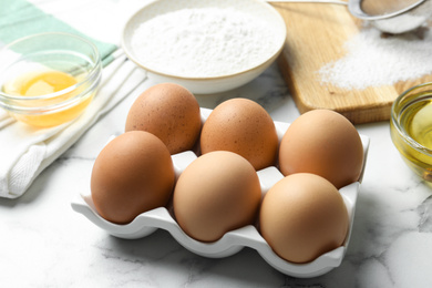 Photo of Brown chicken eggs on white marble table