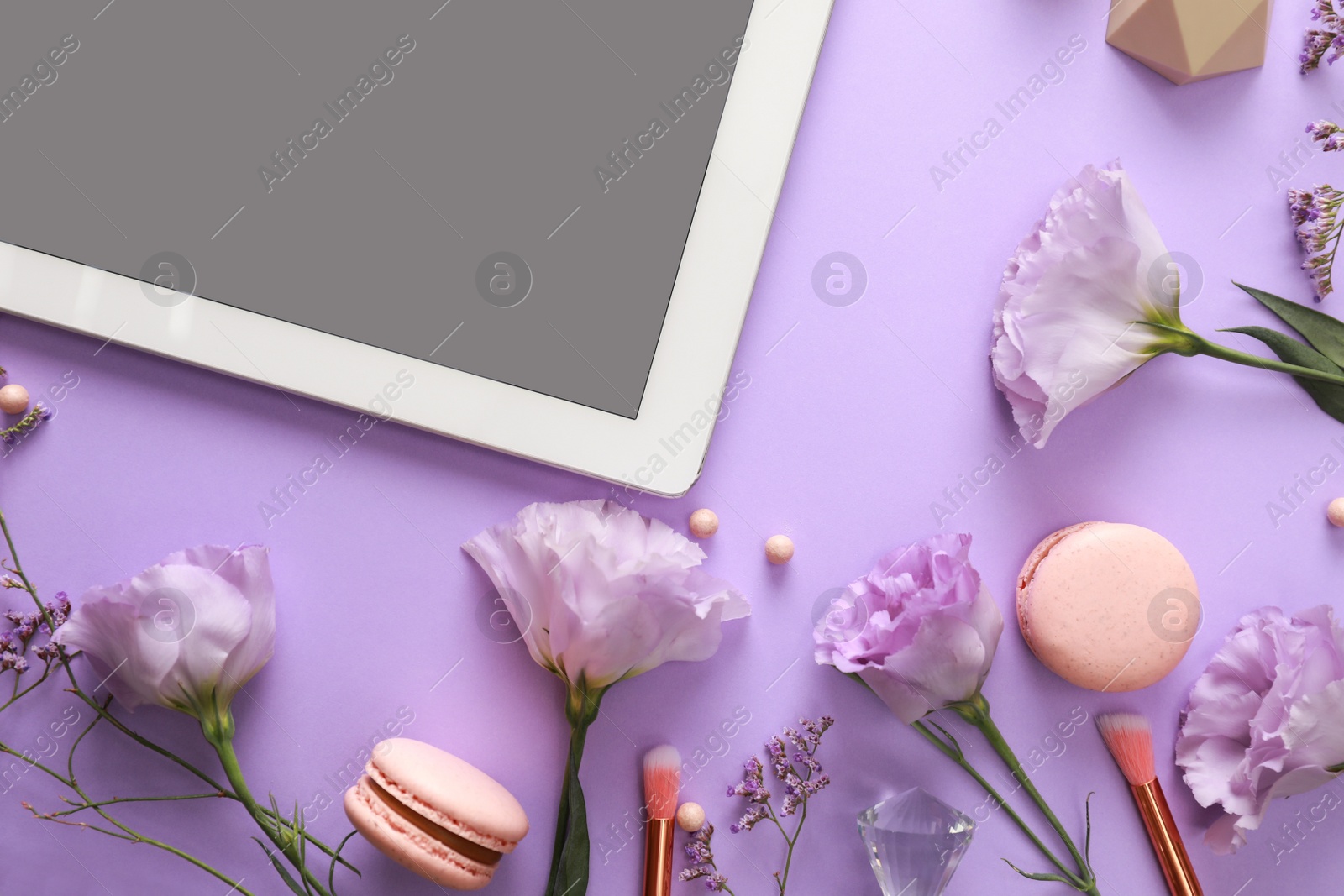 Photo of Flat lay composition with tablet on lilac background. Beauty blogger's workplace