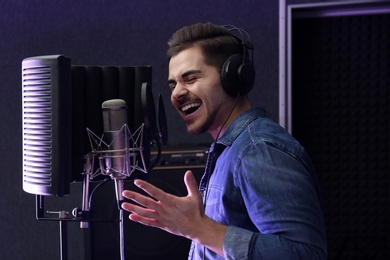 Photo of Young singer with microphone recording song in studio