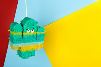 Cactus shaped pinata hanging on color background. Space for text