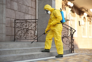 Photo of Person in hazmat suit disinfecting stairs with sprayer outdoors. Surface treatment during coronavirus pandemic