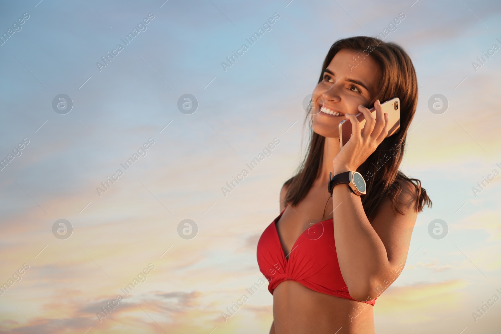 Photo of Young woman with smart watch talking on phone outdoors