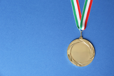 Gold medal on blue background, top view. Space for design