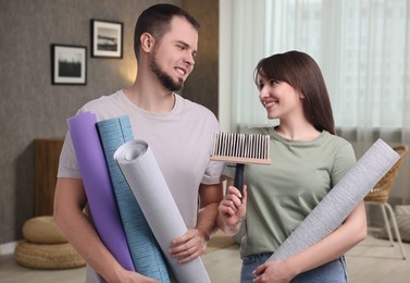 Couple with wallpaper rolls and brush in room
