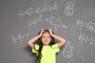 Little school child and mathematical formulas on grey background