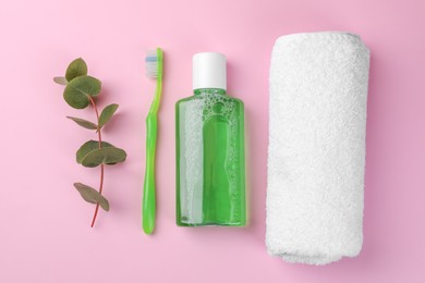 Photo of Flat lay composition with fresh mouthwash in bottle, towel and toothbrush on pink background