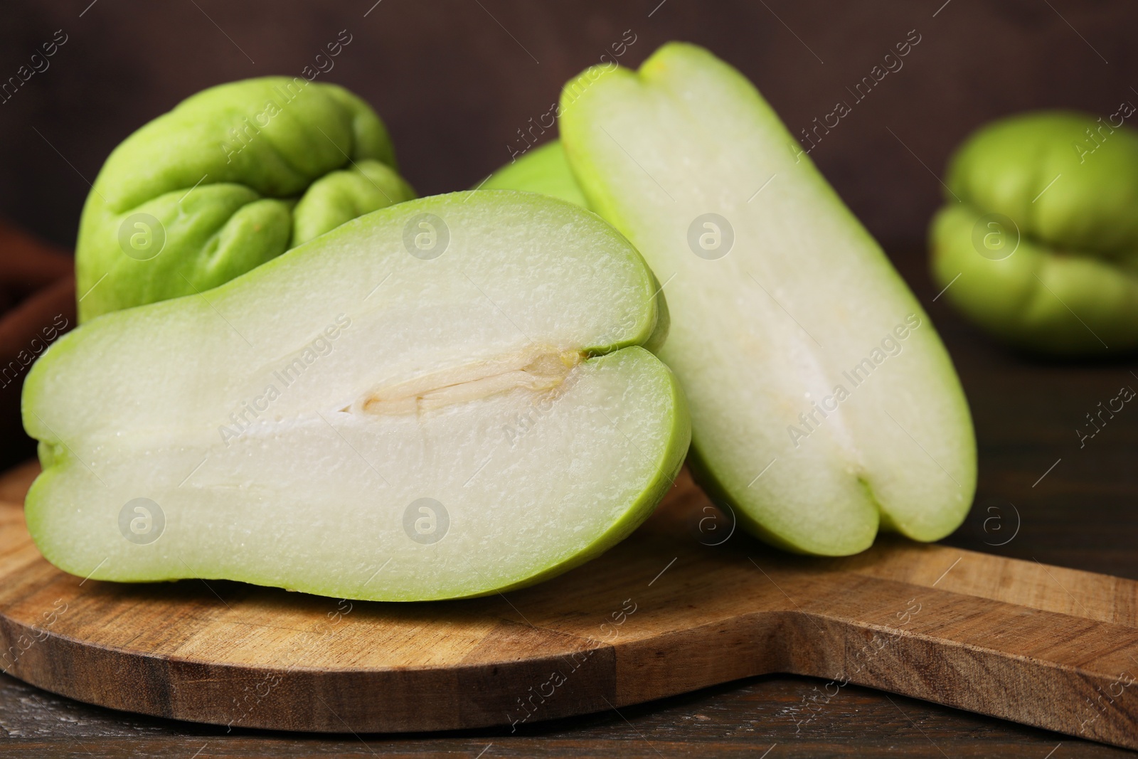 Photo of Cut and whole chayote on wooden table, closeup