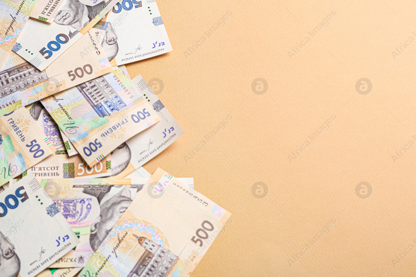 Photo of 500 Ukrainian Hryvnia banknotes on beige background, flat lay. Space for text