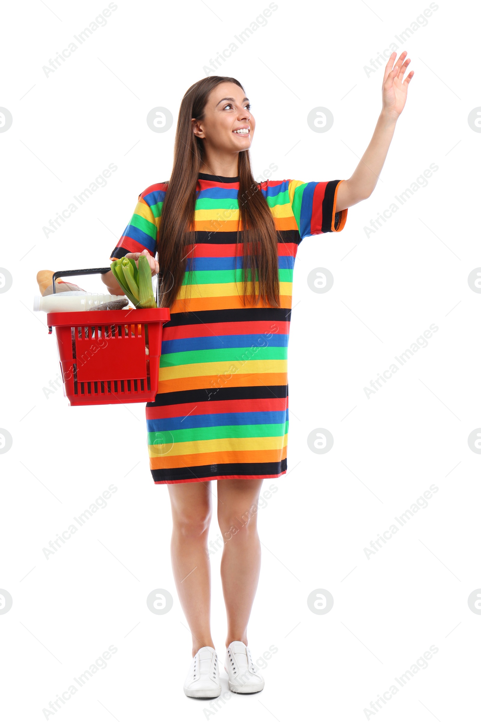 Photo of Young woman with shopping basket full of products isolated on white