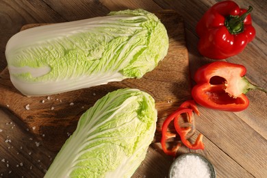 Photo of Fresh Chinese cabbages, bell peppers and salt on wooden table, flat lay