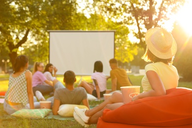 Young people with popcorn watching movie in open air cinema. Space for text