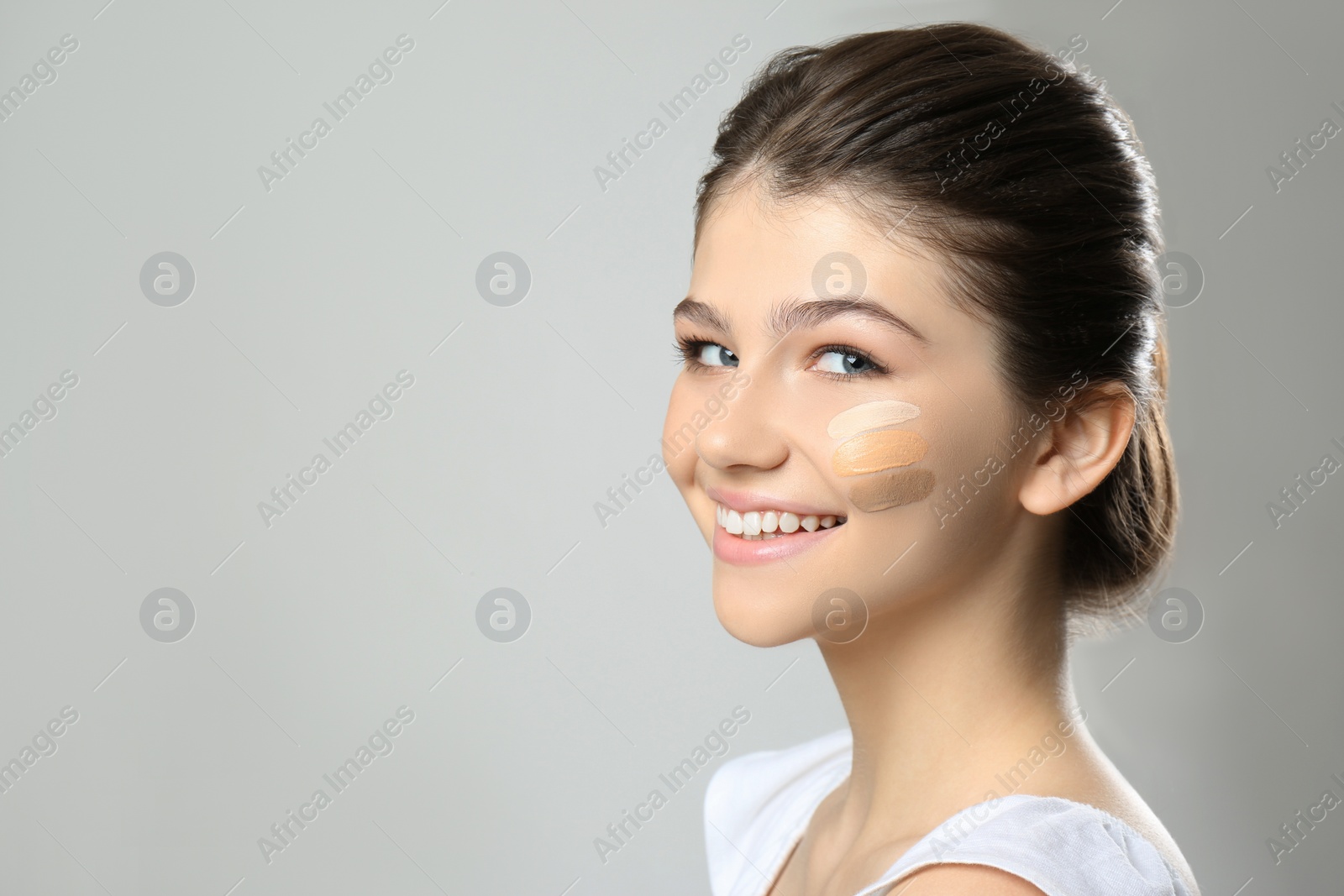 Photo of Beautiful girl on light grey background. Using concealers and foundation for face contouring