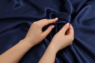 Photo of Woman touching smooth silky fabric, top view
