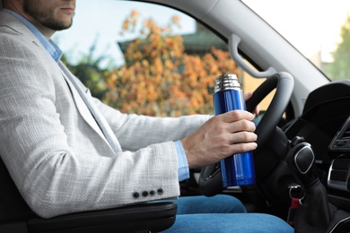 Photo of Man with thermos driving car, closeup view