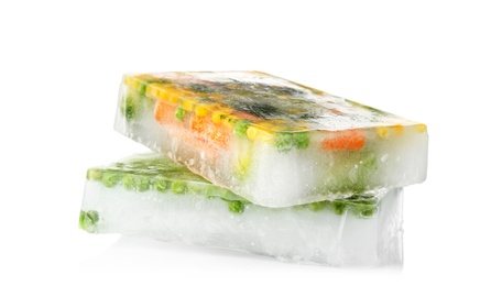 Photo of Fresh vegetables frozen in ice cubes on white background