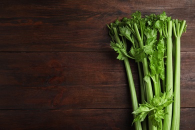 Photo of Fresh green celery on wooden table, top view. Space for text