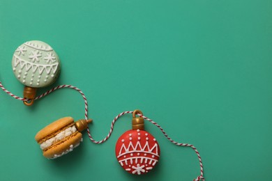 Photo of Beautifully decorated Christmas macarons with rope on turquoise background, flat lay. Space for text