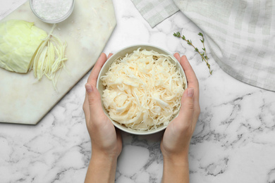 Woman with fermented cabbage at white marble table, top view