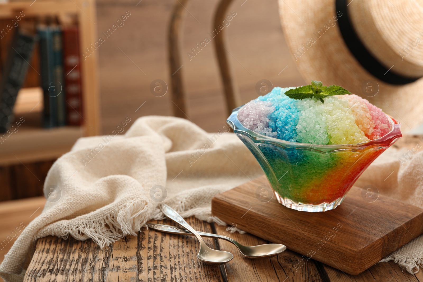 Photo of Rainbow shaving ice in glass dessert bowl on wooden  table indoors