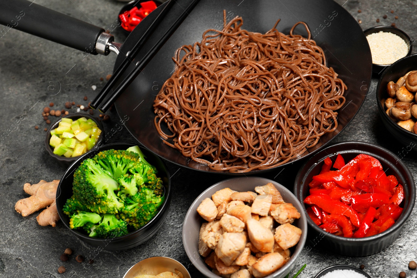 Photo of Wok with noodles, chicken and other products on grey table