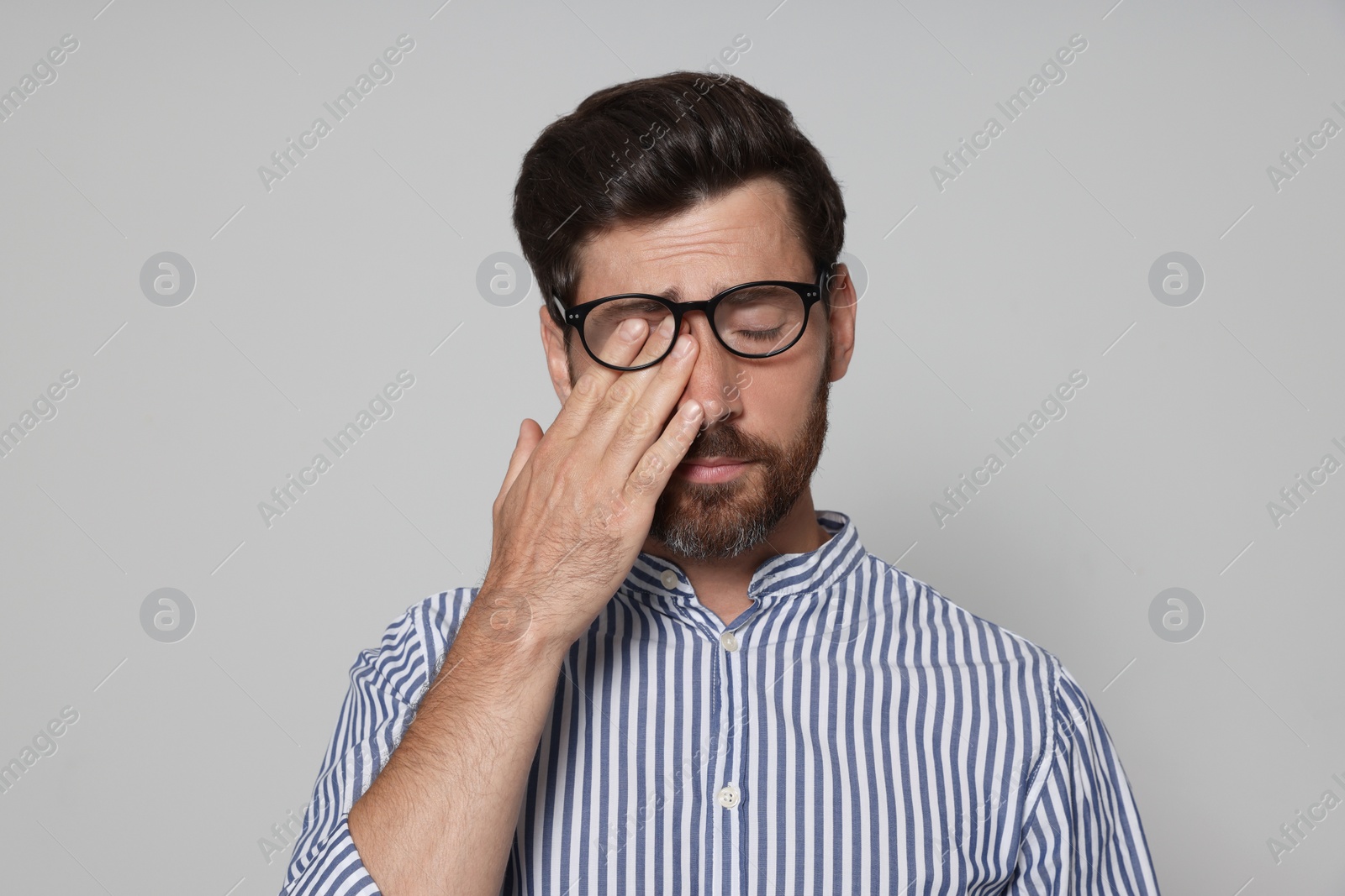 Photo of Man suffering from eyestrain on light grey background