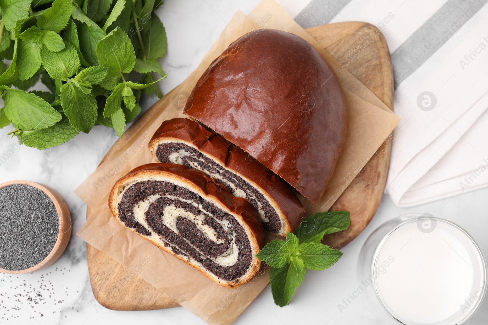 Photo of Cut poppy seed roll served on white marble table, flat lay. Tasty cake