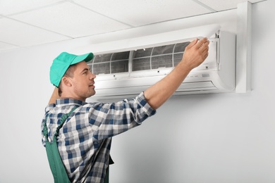 Male technician installing air conditioner indoors