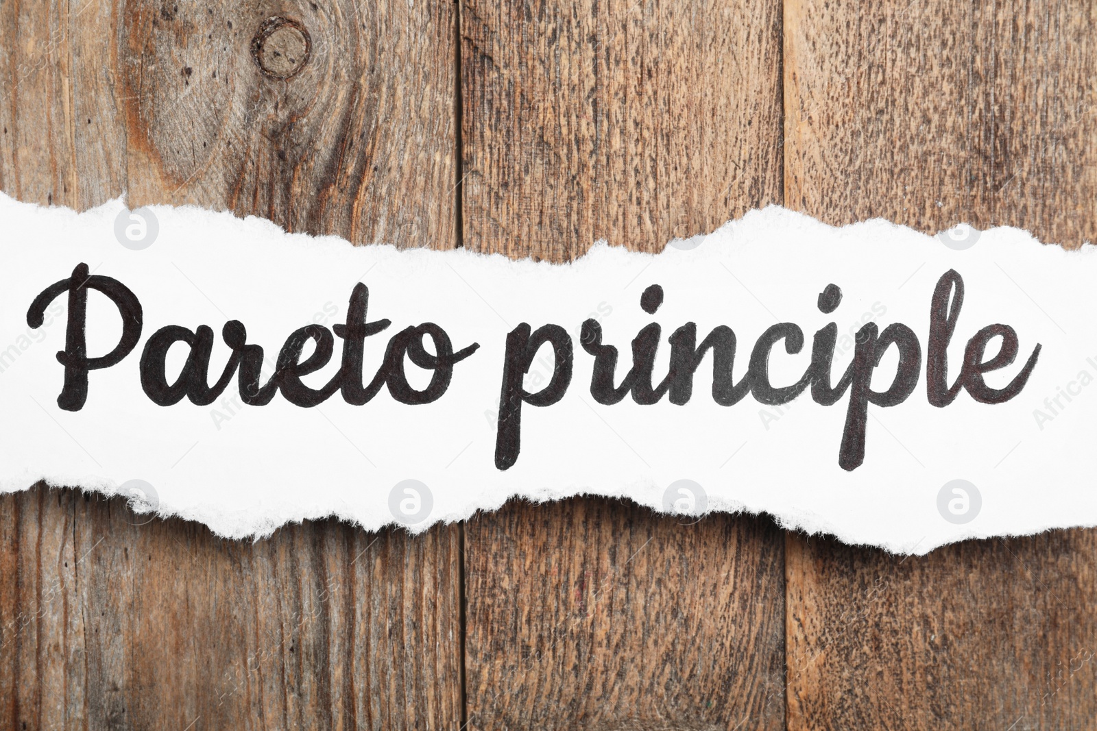 Photo of Sheet of paper with words PARETO PRINCIPLE on wooden background, top view